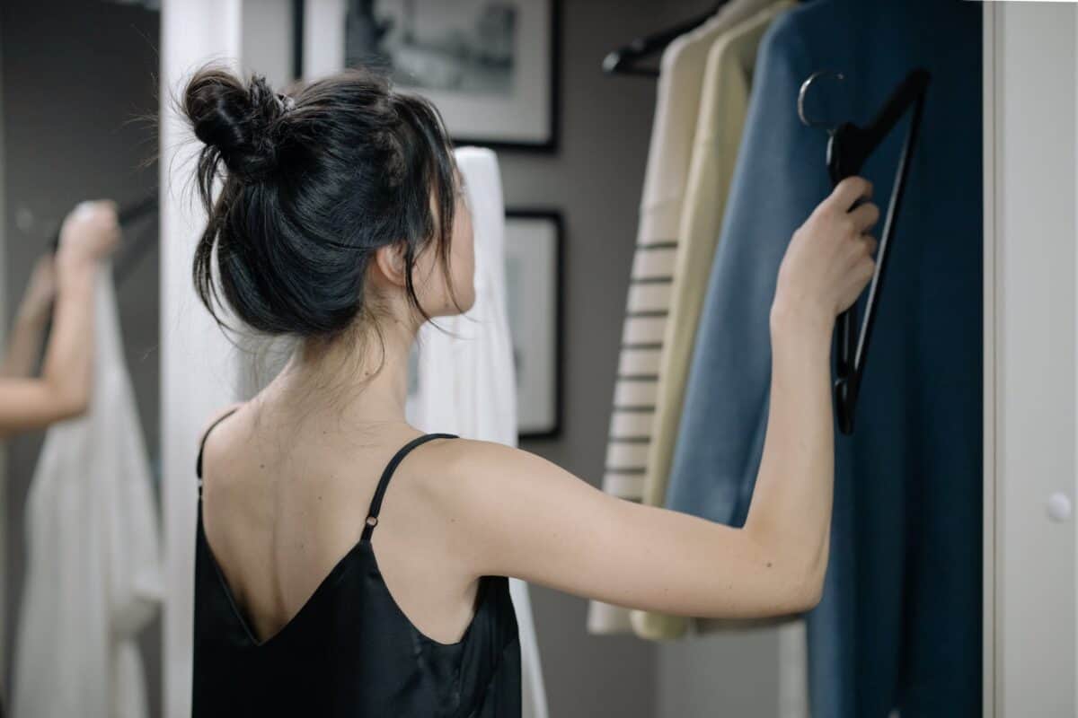 woman in black spaghetti nightdress putting a hanger inside a closet