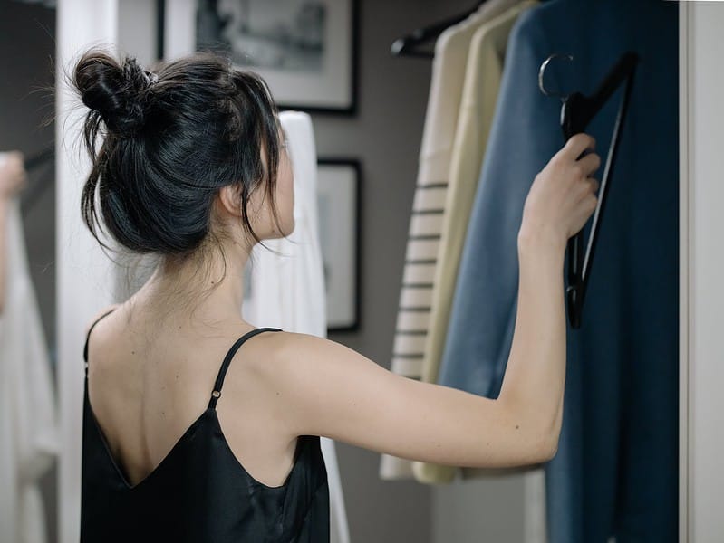 woman in black spaghetti nightdress putting a hanger inside a closet