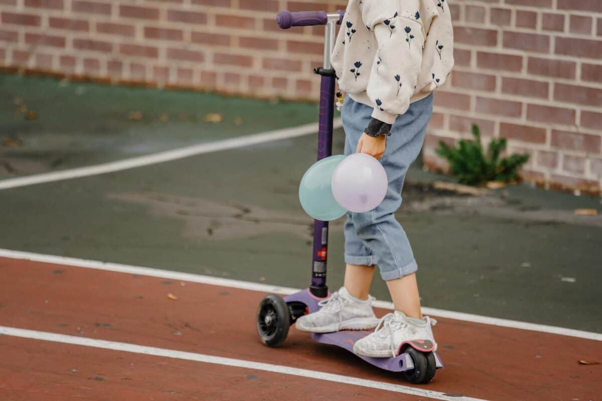 anonymous child sitting on skateboard outside