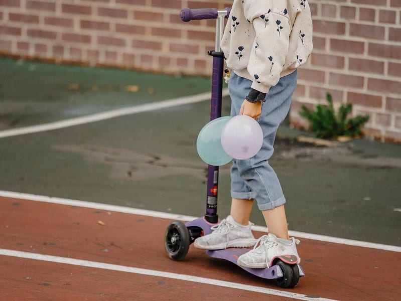 anonymous child sitting on skateboard outside