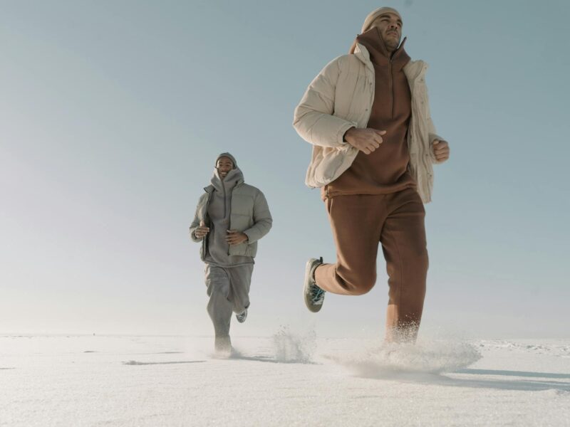 man wearing puffer jackets running on thick snow